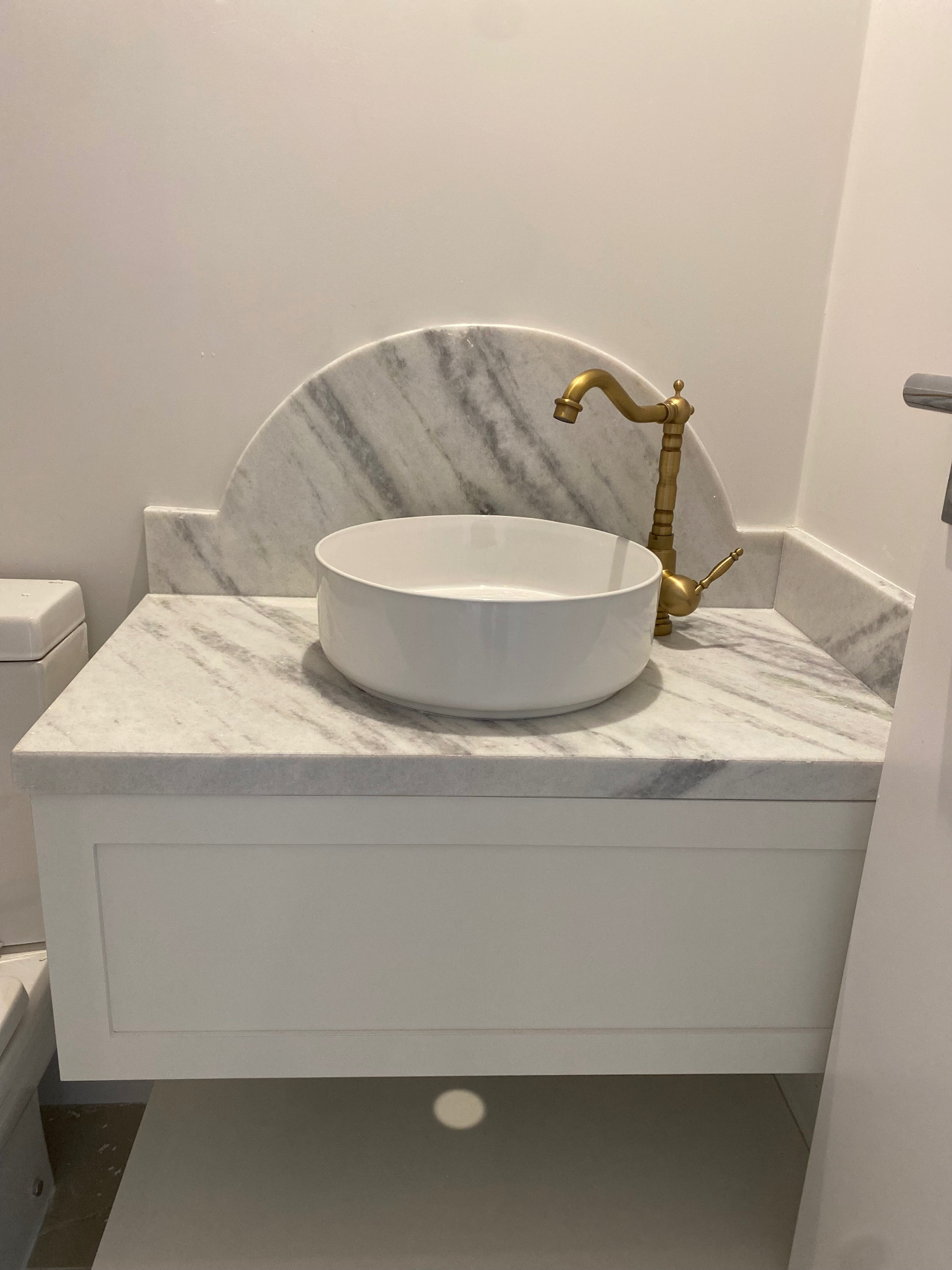 Banheiro com bancada e frontão em mármore branco veiado